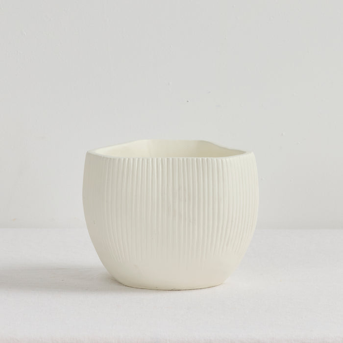 White ceramic pot with ribbed texture on a light gray background