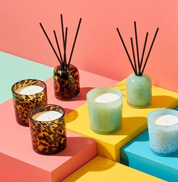 Aurora Candle - Mandarin Spice, white wax candle in a soft green glass vessel, styled with colourful candles and reed diffusers