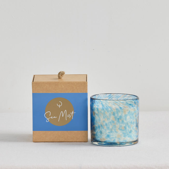 Aurora Candle - Sea Mist, mottled blue and gold glass home fragrance candle beside its kraft gift box.