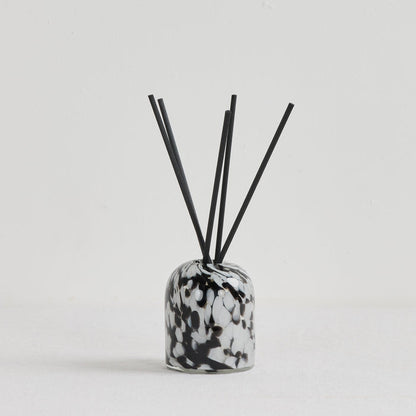 Aurora Diffuser - Vanilla Passionfruit reed diffuser in a mottled black, white and grey glass vessel with black reeds