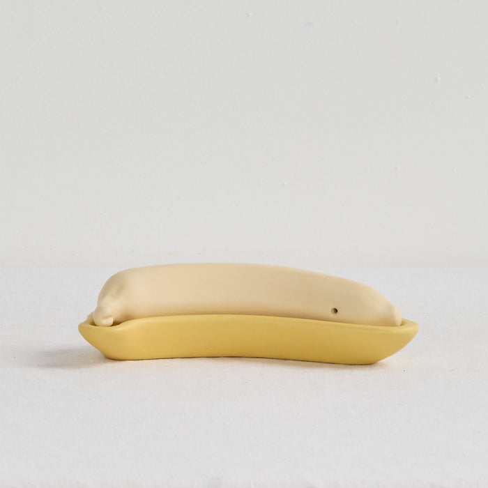 Yellow ceramic object resembling a fish on a light gray background