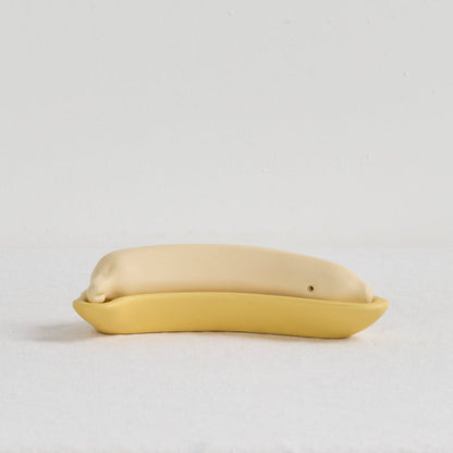 Yellow ceramic object resembling a fish on a light gray background
