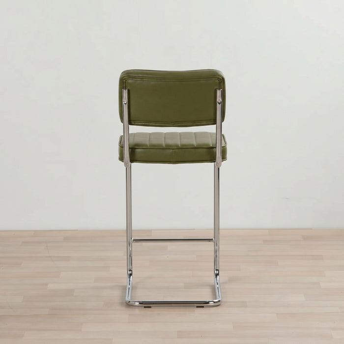 Green bar stool with metal frame on a wooden floor and light gray wall background