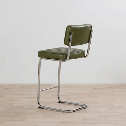Green bar stool with chrome frame on a wooden floor and light gray background