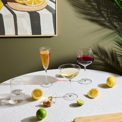 Bravo Coupe Glass Set - 2pc - Clear, lightly fluted clear coupe glass with a pale cocktail on a sunlit table
