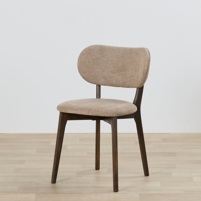 Beige upholstered chair with wooden legs on a light wooden floor and white wall background