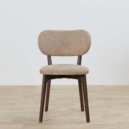 Beige upholstered chair with wooden legs on a light wood floor and white wall background
