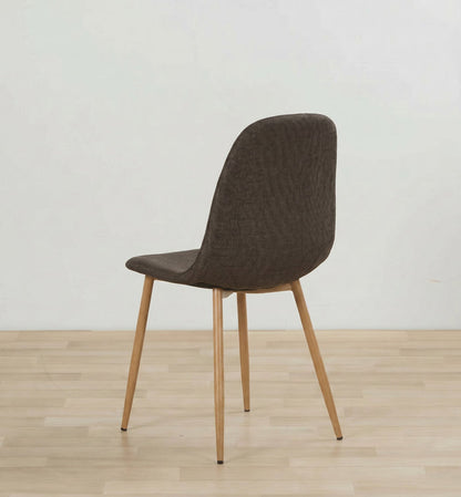 A modern dining chair with a textured dark brown upholstered seat and backrest, supported by four tapered light wood legs, shown on a light wood floor against a plain white wall.