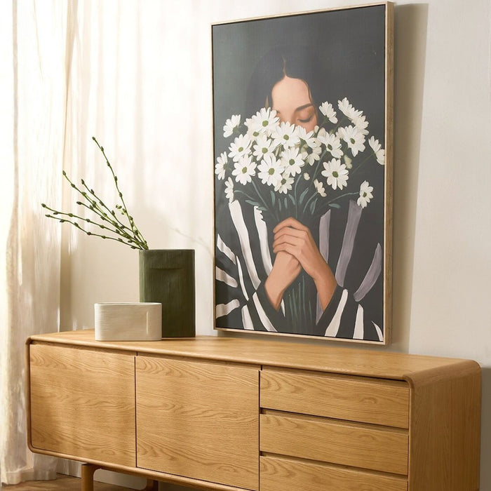 Hands Full Artwork - Green/white, framed wall art of a woman holding white daisies, styled above a timber sideboard.