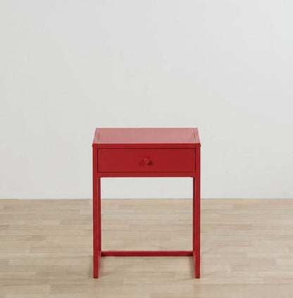 Red side table with a drawer on a wooden floor and light gray wall background