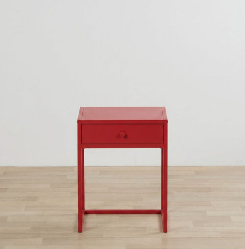 Red side table with a drawer on a wooden floor and light gray wall background