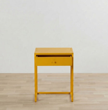 Yellow side table with a drawer on a wooden floor and light gray wall background