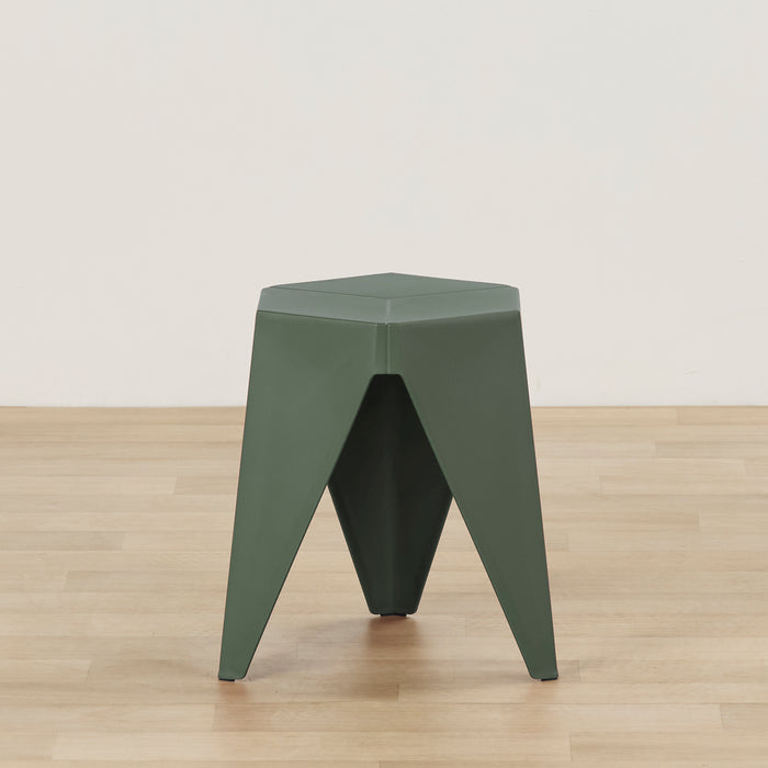 A dark green geometric stool with a hexagonal top and three angled legs, shown on a light wood floor against a plain off-white wall.