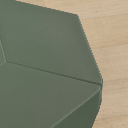 Close-up of a dark green geometric hexagonal stool top with a matte finish, set against a light wood floor background.
