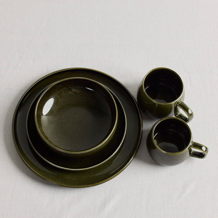 Green stacked dinnerware with green mugs on a white tablecloth