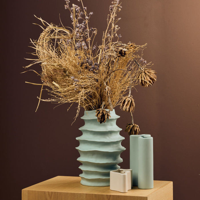 Organic Rib Vase - Sage sculptural ribbed green vase styled with dried botanicals on a timber plinth.