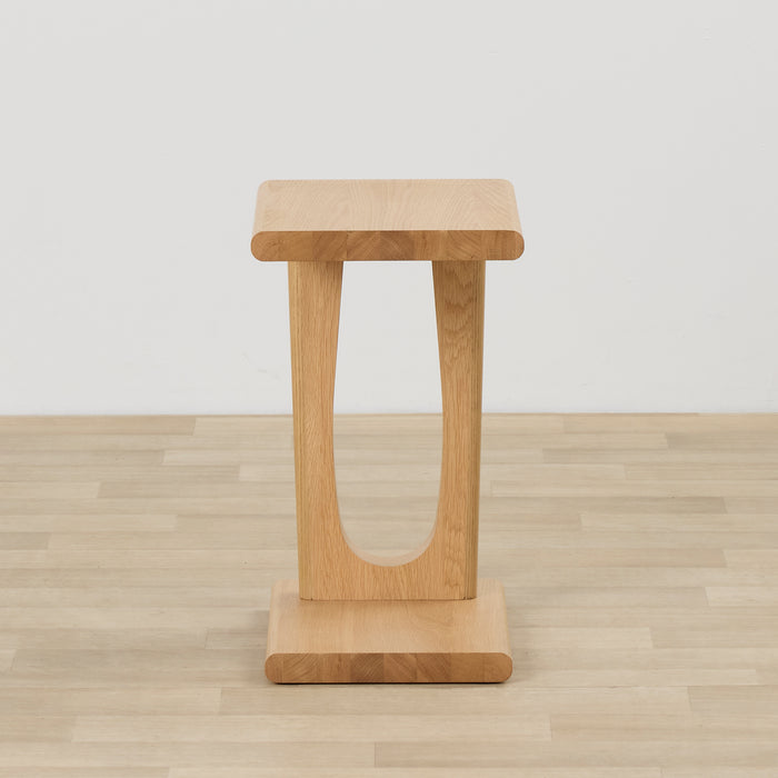 Samson End Table - Oak side table with a rounded oak top, sculptural U-shaped base and plinth foot on timber flooring