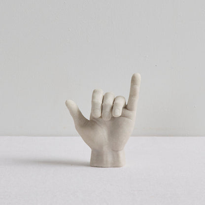 Shaka Hand Object - Bone sculptural ornament in a playful hang loose hand gesture on a white surface