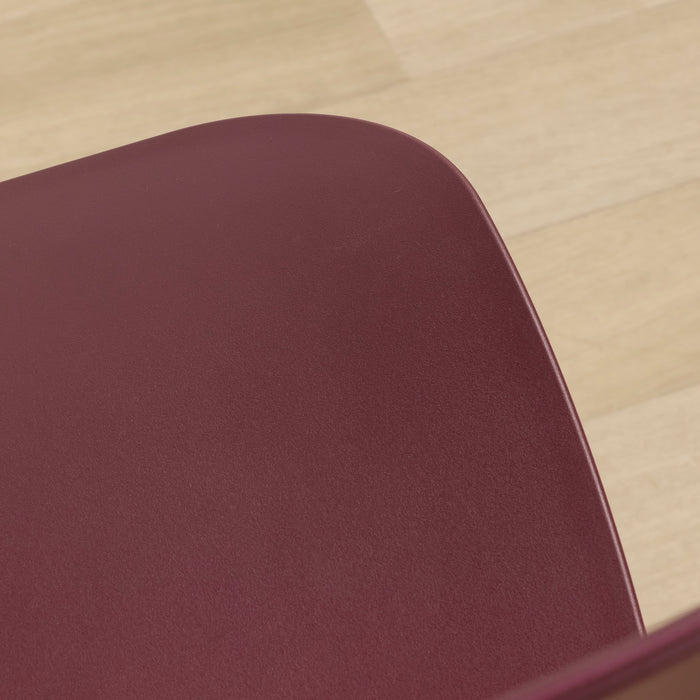 Vincent Dining Chair - Wine, close-up of the curved wine-coloured plastic seat against a timber floor.